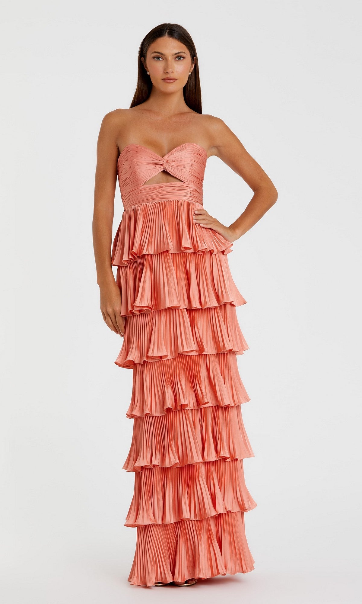 A woman stands against a plain background wearing the Mac Duggal 49981 long formal dress in terra cotta, featuring a strapless twisted front detail and an elegant, tiered column silhouette.